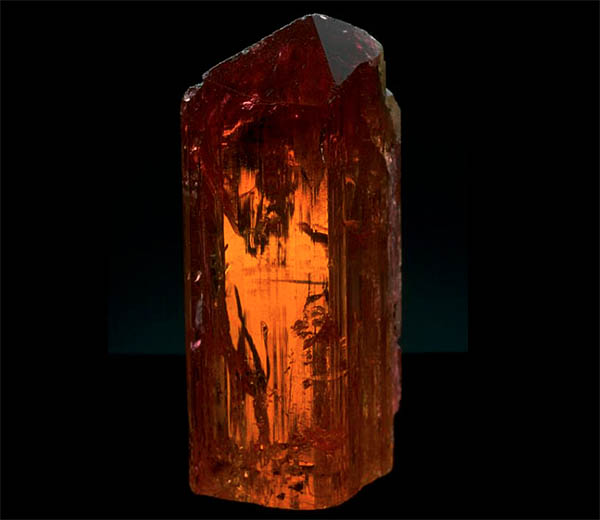 Close-up image of a natural amber crystal with a rich orange hue, showcasing its intricate texture and sharp edges.