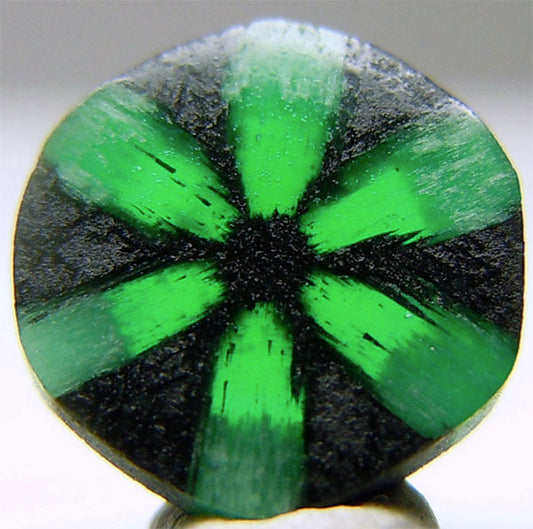 Close-up view of a green and black star-shaped gemstone with radiating lines and unique pattern.