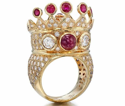 Gold crown ring adorned with ruby gemstones and diamonds, featuring a central red stone surrounded by intricate details and sparkling gems.