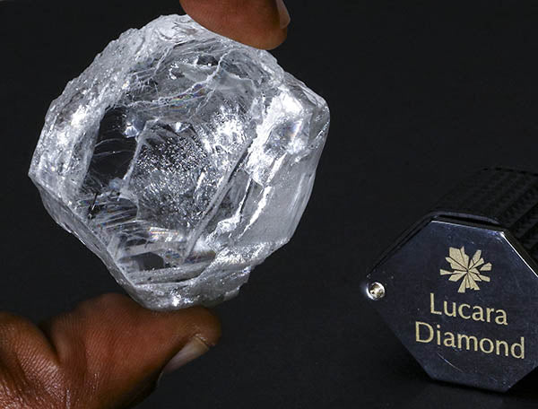 Lucara diamond being held by hand, showing a large, clear rough diamond next to a Lucara Diamond label, showcasing the size and clarity of the gemstone.