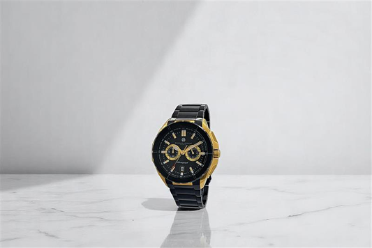 "A black and gold wristwatch with a black metal strap, dual subdials, and a black face, standing upright on a white marble surface with a minimalist light gray background