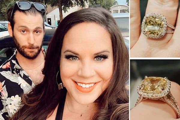 Couple posing for a selfie with a close-up of the woman's engagement ring featuring a large yellow cushion-cut diamond surrounded by smaller diamonds.