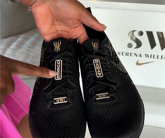 Serena Williams' custom black sneakers featuring 'QUEEN' on one shoe and 'MAMA' on the other, with golden accents and her 'SW' logo visible.